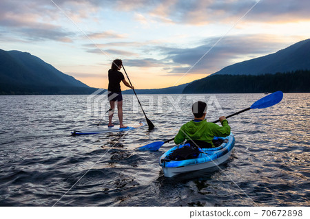 Friends on Scenic Lake Kayaking and Paddleboarding Together 70672898