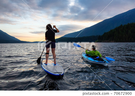 Friends on Scenic Lake Kayaking and Paddleboarding Together 70672900