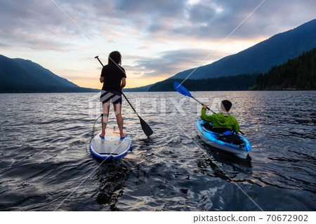Friends on Scenic Lake Kayaking and Paddleboarding Together 70672902