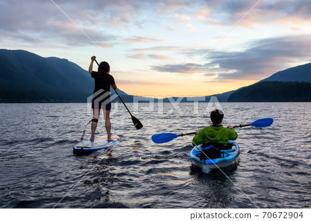 Friends on Scenic Lake Kayaking and Paddleboarding Together 70672904