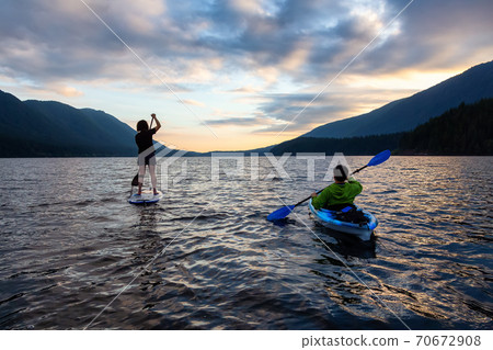 Friends on Scenic Lake Kayaking and Paddleboarding Together 70672908