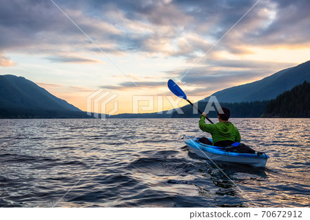 Beautiful View of Person Kayaking on Scenic Lake at Sunset 70672912