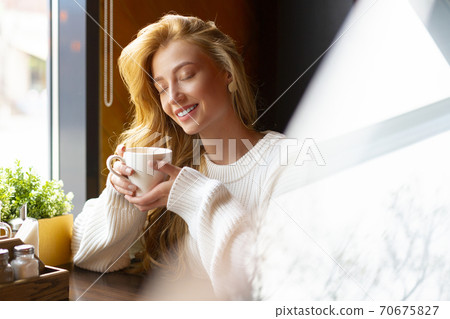 Woman at a cafe drinks tea. Close up portrait. Woman at a cafe drinks tea. Close up portrait. 70675827