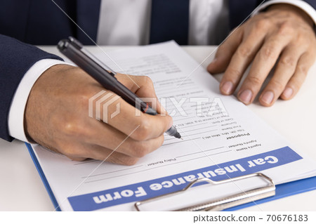 Zoom Insurance Agent Hand Writing Car Insurance Claim Form or Document at Side View 70676183