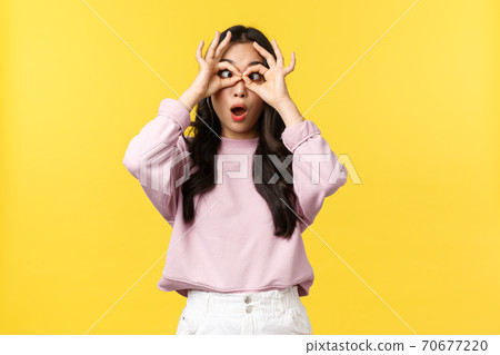Lifestyle, emotions and advertisement concept. Funny and playful cute asian girl fooling around, make fake glasses with hands over eyes and squinting, showing tongue, standing yellow background 70677220