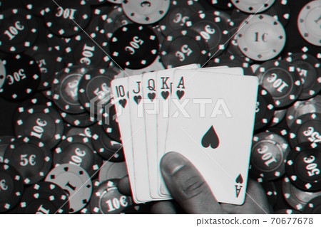 Royal flush in the hands of the player on the background of game chips Royal flush in the hands of the player on the background of game chips 70677678