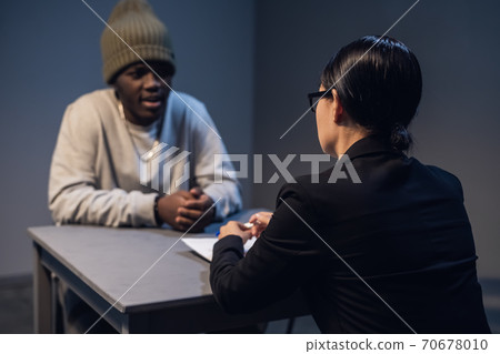 A black guy listens to his rights from a civil lawyer at a table in a visiting room in a state prison 70678010