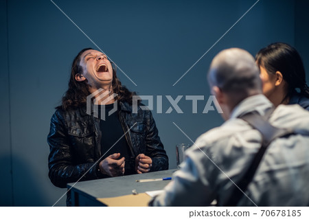 Young police officers are interrogating, the suspect laughs audaciously Young police officers are interrogating, the suspect laughs audaciously 70678185