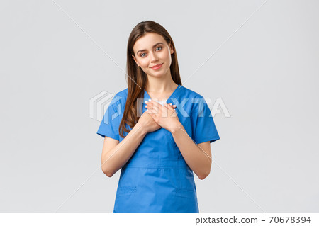 Healthcare workers, prevent virus, insurance and medicine concept. Touched and flattered female nurse or doctor in blue scrubs, tilt head and touch heart, smile from compliment, nice gesture Healthcare workers, prevent virus, insurance and medicine concept. Touched and flattered female nurse or doctor in blue scrubs, tilt head and touch heart, smile from compliment, nice gesture 70678394