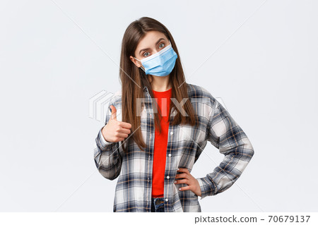 Coronavirus outbreak, leisure on quarantine, social distancing and emotions concept. Confident good-looking woman in medical mask give advice, recommend promo, show thumb-up in approval 70679137