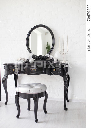 Black boudoir table in a bright room with a white brick wall. 70679393