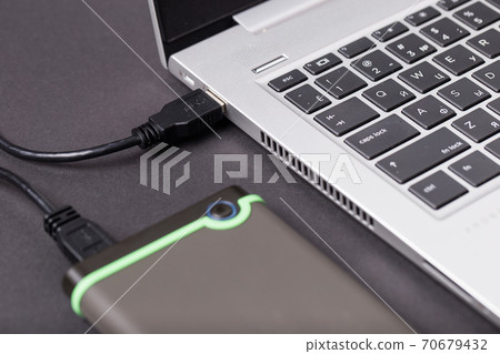 Hard disk and laptop on a black table close-up. Hard disk and laptop on a black table close-up. 70679432