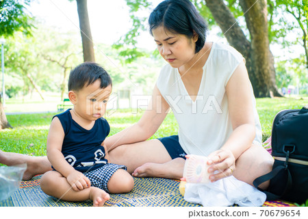 Mom playing with baby boy in city green park 70679654