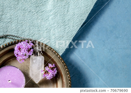 Clear quartz crystal charm with vervain flowers and a scented candle, shot from the top with copy space 70679690