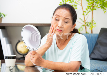 Senior woman worried looking in the mirror 70680718