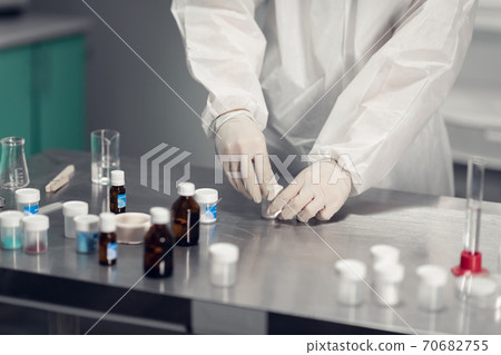 Close-up of a man studying a chemical reaction on a lab table with lab tools and colorful liquids Close-up of a man studying a chemical reaction on a lab table with lab tools and colorful liquids 70682755