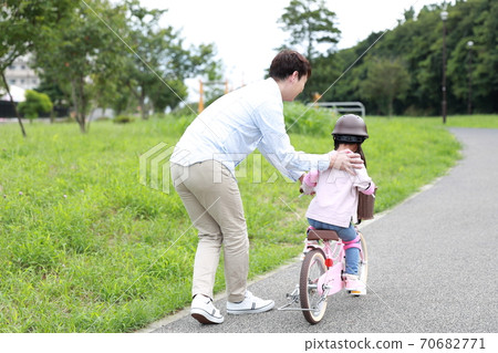 Parents and children practicing by taking training wheels on their bicycles Parents and children practicing by taking training wheels on their bicycles 70682771