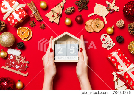 Top view of female hands holding calendar on red background. The twenty fifth of December. Holiday decorations. Christmas time concept 70683756