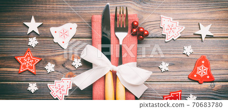 Top view of fork and knife on napkin on wooden background. Banner Different christmas decorations and toys. Close up of New Year dinner concept Top view of fork and knife on napkin on wooden background. Banner Different christmas decorations and toys. Close up of New Year dinner concept 70683780