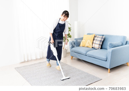 Woman Cleaning Living Room With Vacuum Cleaner Stock Photo