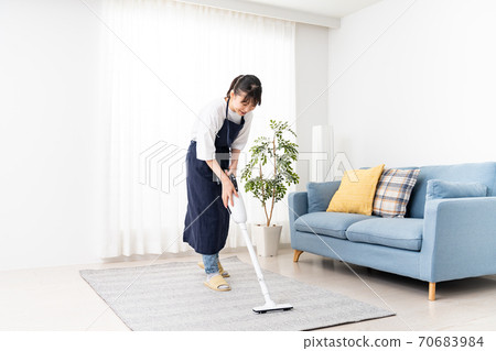 Woman Cleaning Living Room With Vacuum Cleaner Stock Photo