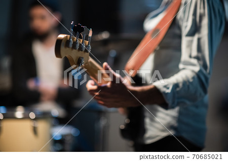 a member of a rock band at a jam session performs a musical part on bass guitar. a member of a rock band at a jam session performs a musical part on bass guitar. 70685021