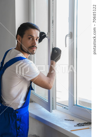 Male artisan installs a window in the room 70685122