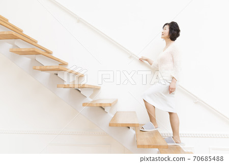 Senior woman climbing stairs 70685488
