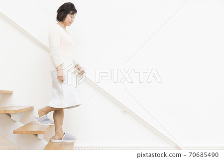 Senior woman going down the stairs 70685490