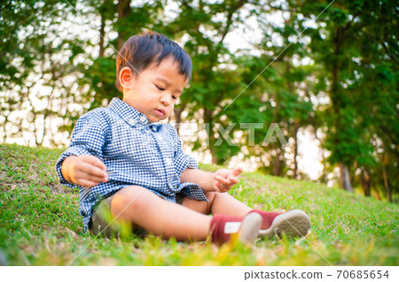Adorable child boy sitting inder tree playing toy in summer park 70685654