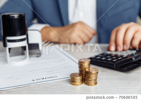 Businessman approves important contract. Stack of coins and stamps on desk. Business concept 70686585