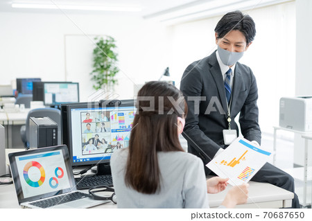 Corona Sorrow: An office worker wearing a mask who asks his boss for instructions while having a web conference 70687650