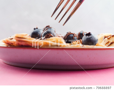 Eating crepes with chocolate and blueberries Eating crepes with chocolate and blueberries 70688897