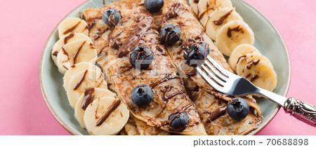 Crepes with chocolate nut spread, banana, berries Crepes with chocolate nut spread, banana, berries 70688898