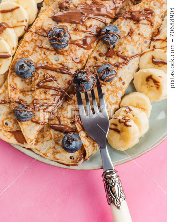 Crepes with chocolate nut spread, banana, berries 70688903