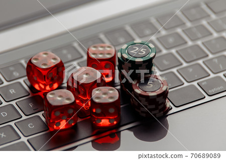 Online casino concept. Gambling chips and five red dices on laptop keyboard close-up Online casino concept. Gambling chips and five red dices on laptop keyboard close-up 70689089