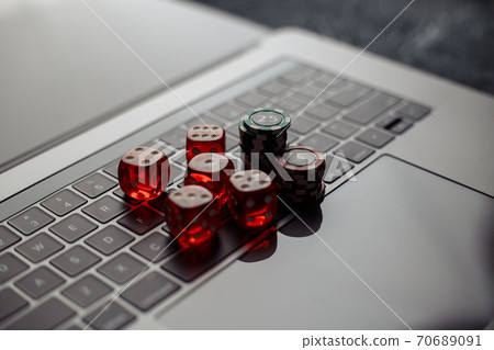 Online casino theme. Gambling chips and five red dices on laptop keyboard Online casino theme. Gambling chips and five red dices on laptop keyboard 70689091