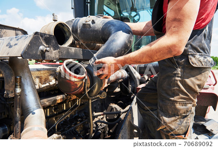 Combine machine service, mechanic repairing motor outdoors Combine machine service, mechanic repairing motor outdoors 70689092