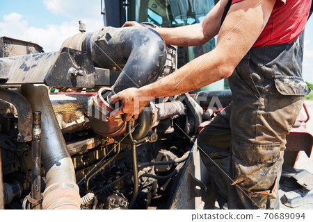Combine machine service, mechanic repairing motor outdoors Combine machine service, mechanic repairing motor outdoors 70689094