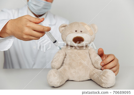 Pediatrician makes an injection for sick teddy bear. Child healtcare and treatment concept Pediatrician makes an injection for sick teddy bear. Child healtcare and treatment concept 70689095