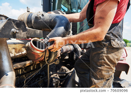 Combine machine service, mechanic repairing motor outdoors Combine machine service, mechanic repairing motor outdoors 70689096