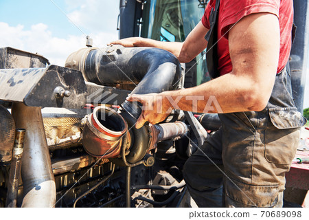 Combine machine service, mechanic repairing motor outdoors Combine machine service, mechanic repairing motor outdoors 70689098