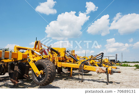 Close up of seeder attached to tractor in field. Agricultural machinery for spring works sowing Close up of seeder attached to tractor in field. Agricultural machinery for spring works sowing 70689131