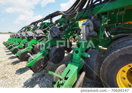 Close up of seeder attached to tractor in field. Agricultural machinery for spring works sowing Close up of seeder attached to tractor in field. Agricultural machinery for spring works sowing 70689147