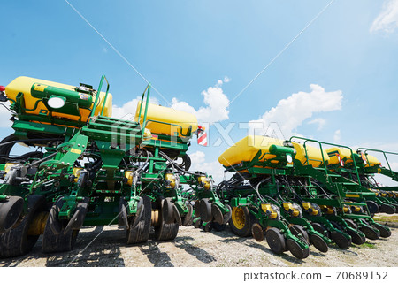 Close up of seeder attached to tractor in field. Agricultural machinery for spring works sowing Close up of seeder attached to tractor in field. Agricultural machinery for spring works sowing 70689152