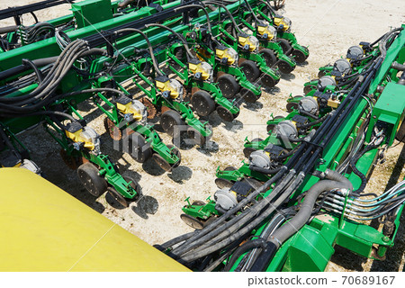Close up of seeder attached to tractor in field. Agricultural machinery for spring works sowing Close up of seeder attached to tractor in field. Agricultural machinery for spring works sowing 70689167
