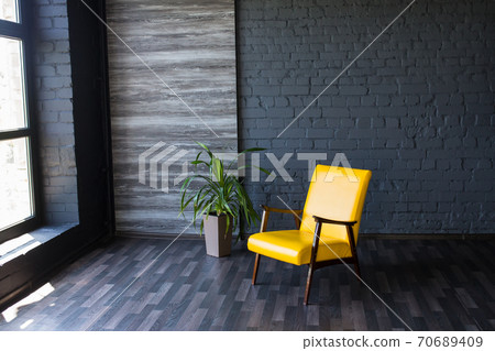 Stylish retro yellow chair in the gray room. Brick gray wall. Room. Stylish retro yellow chair in the gray room. Brick gray wall. Room. 70689409