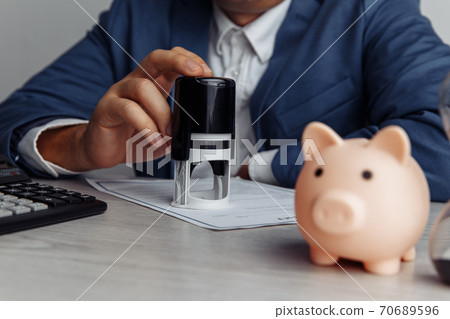 Businessman approves important contract. Piggy bank with stack of coins on desk close-up. Economy, business and management financial concept 70689596