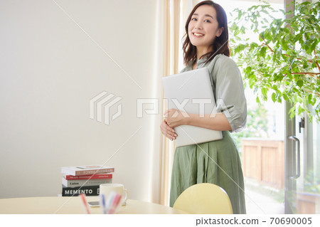 A woman standing with a computer in the living room 70690005