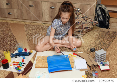 girl draws at home, artistic creation, makes creative artwork from paper, paints and brushes girl draws at home, artistic creation, makes creative artwork from paper, paints and brushes 70690670